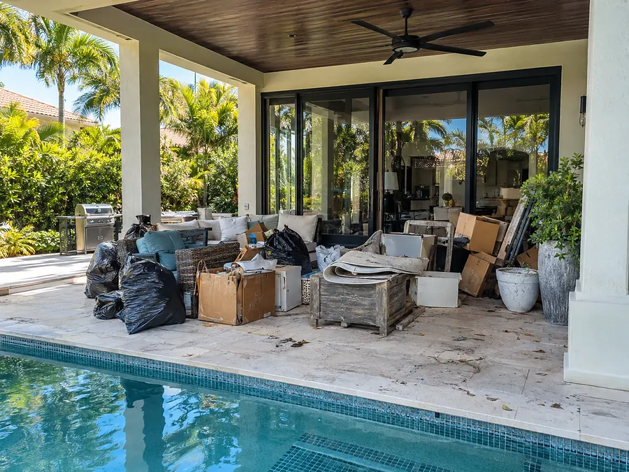 A pool patio buried under old furniture and bags